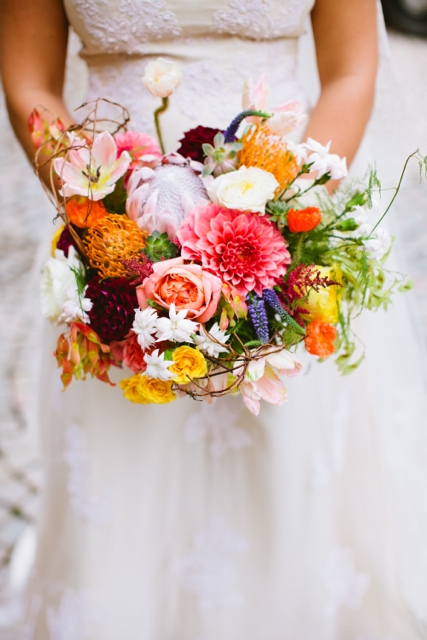 Bridal bouquet by designer Amy Dunlap of Amy Lynn Originals - Winston-Salem, NC, with orange pincushion protea, coral and burgundy dahlias, king protea, blush tulips, yellow spray roses, coral garden roses, succulents, astilbe, veronica and tree of heaven