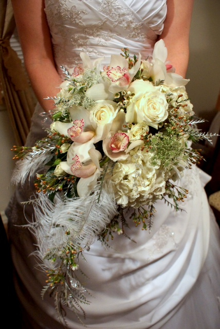 Cascading bridal bouquet by designer Julia Miller of Julia's Floral - Edgewood, Washington, with white hydrangea, white roses, white cymbidium orchids, Queen Anne’s lace, wax flower, grevillea and ostrich feathers